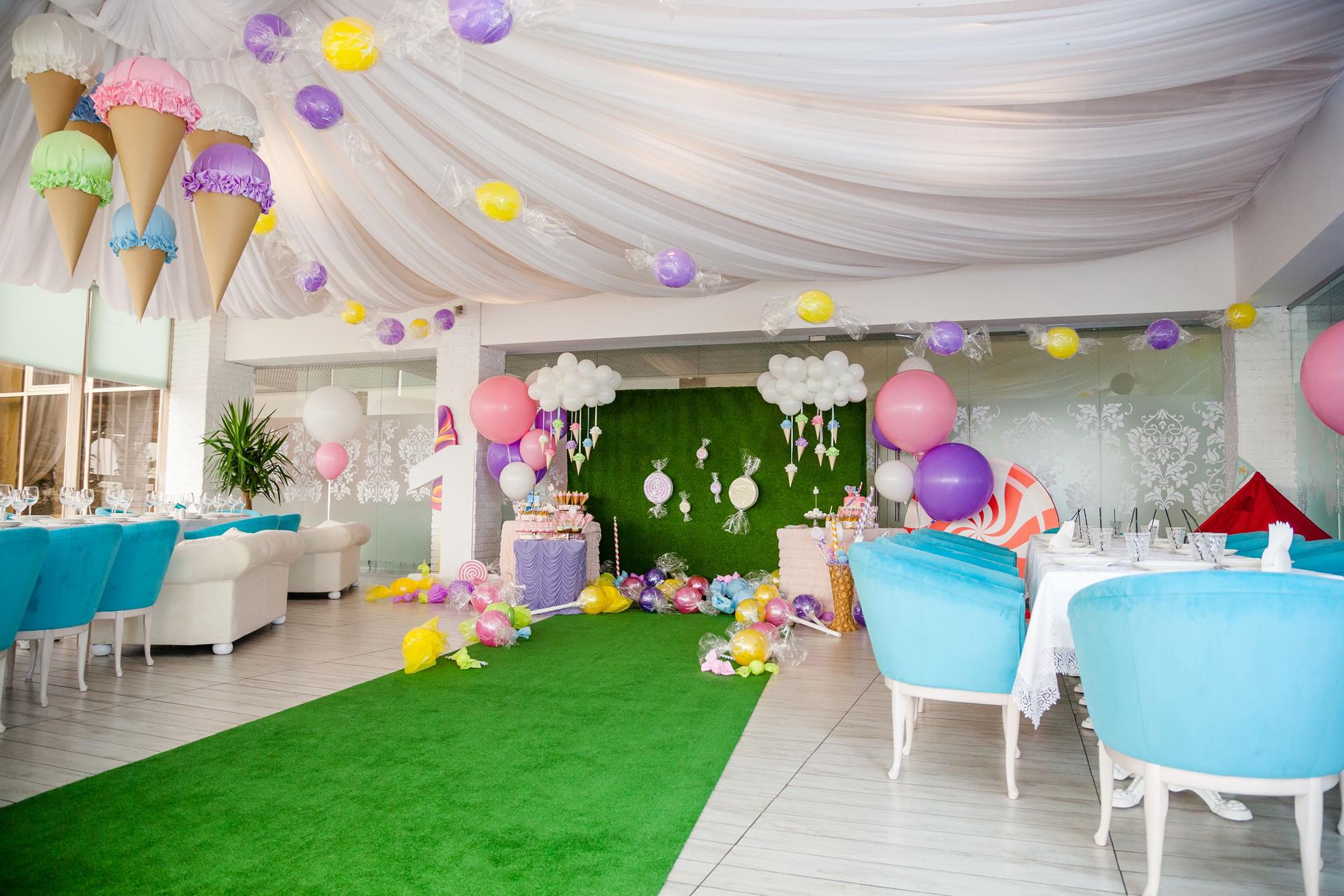 Birthday party concept, decorations for sweet party. Huge number one, table with sweets and desserts, cloud from balloons and ice-creams, a lot of colored balloons and big candy toys