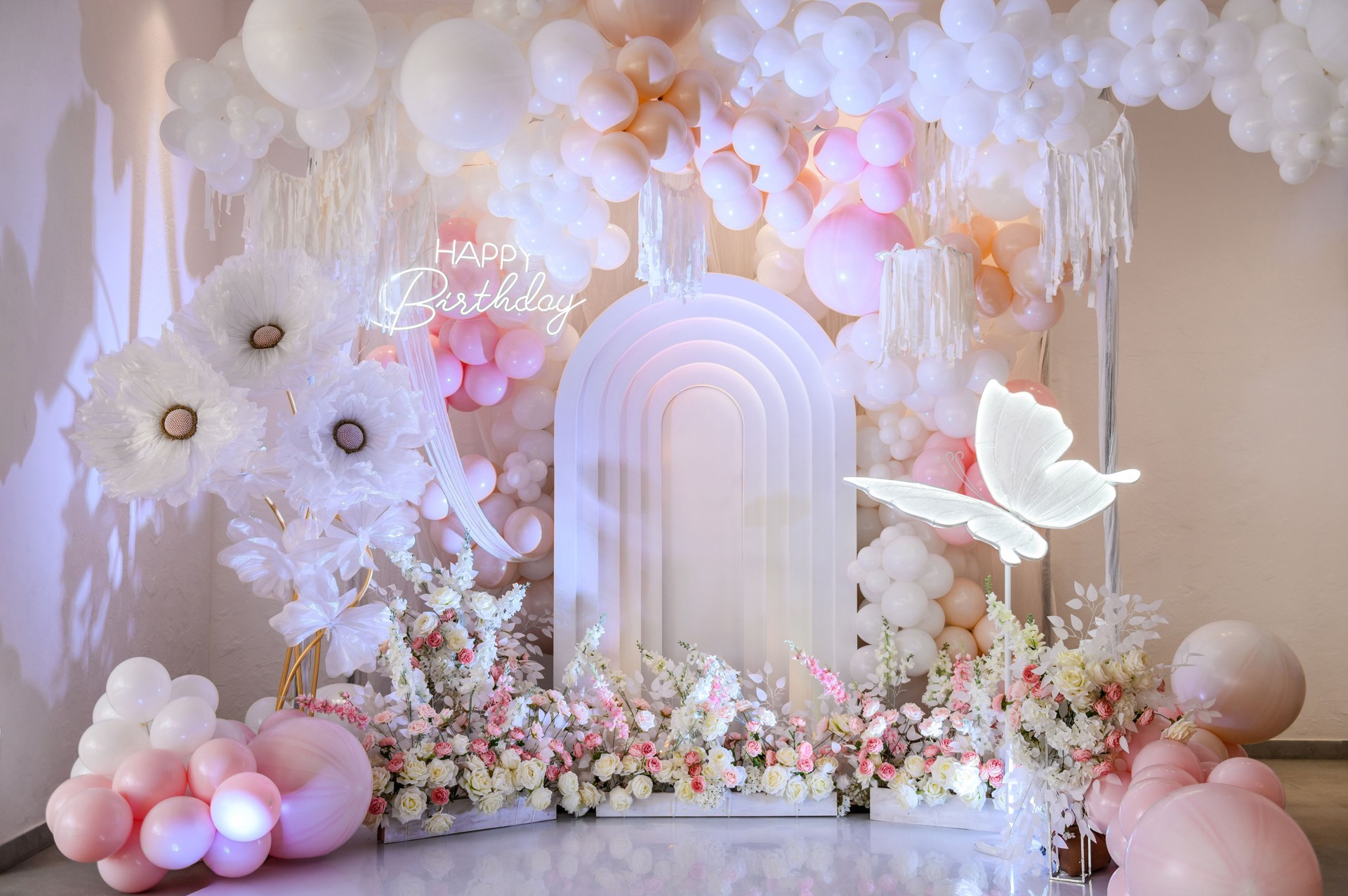Arch decoration pink, white balloons, text Happy Birthday, decorated flowers. Children's photo zone. Decor paper butterfly. Birthday party for baby girl on a background photo wall.